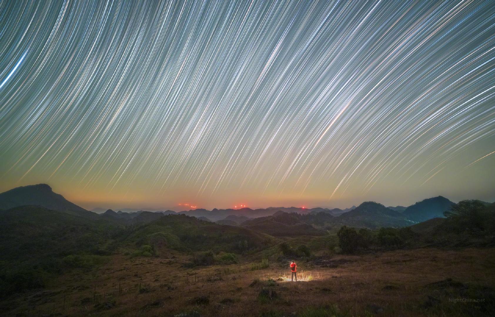 星光不肯停驻，便在长夜里留下一道道奔赴的痕迹。那些细白的弧线，将整片苍穹织成一幅