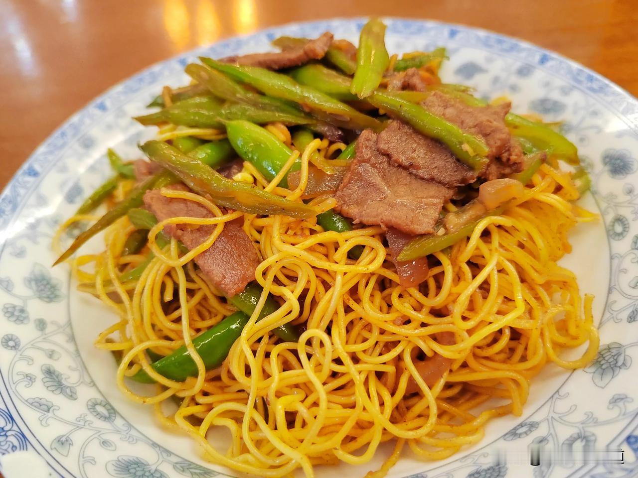 牛肉炒熟加汤，将扁豆平铺在肉上，再把面条平铺在扁豆上，盖盖焖十分钟，翻炒即可。
