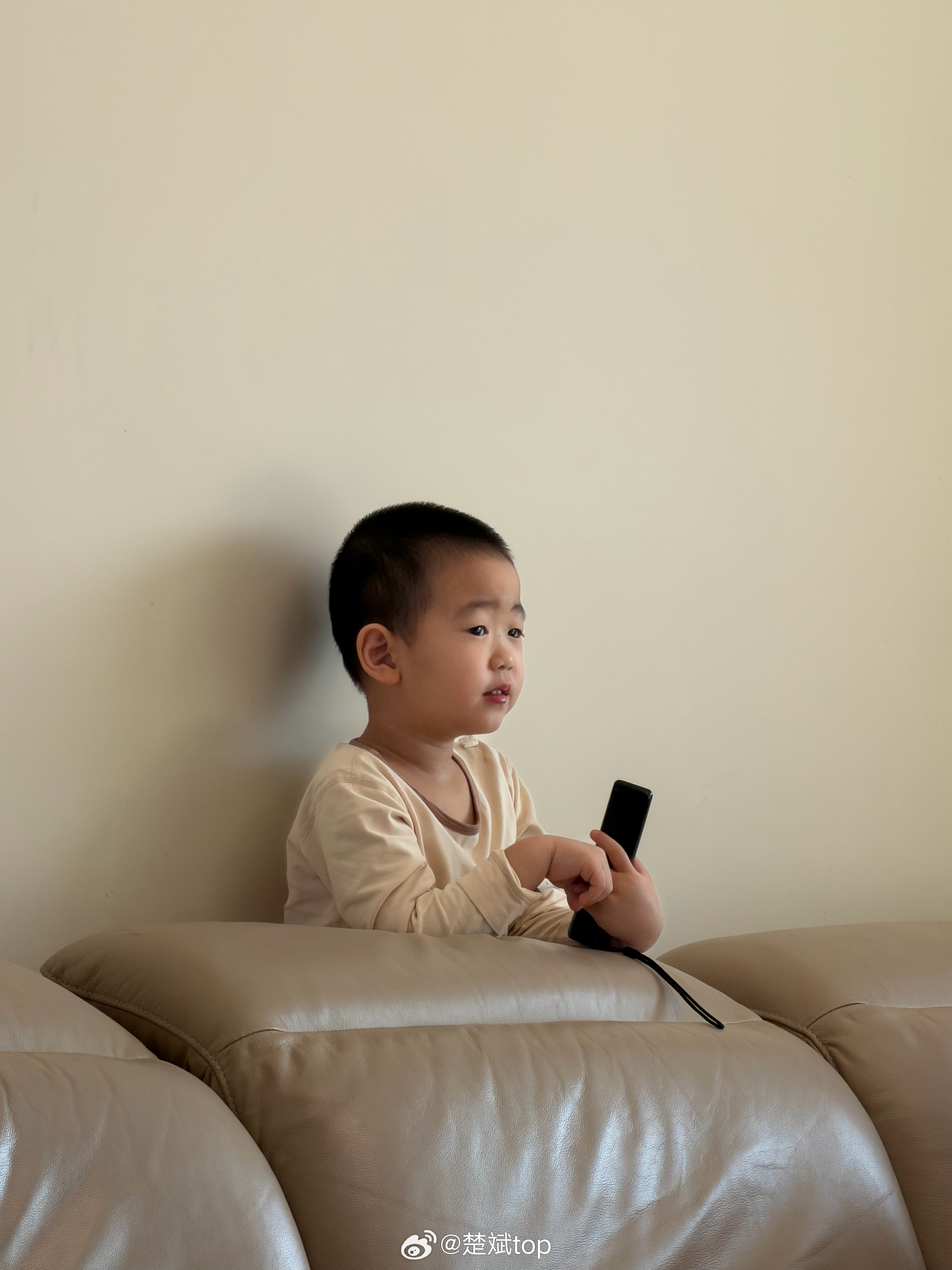 儿子喜欢躲在沙发后面看动画片，他脚下踩的是一堆小熊毛绒玩具