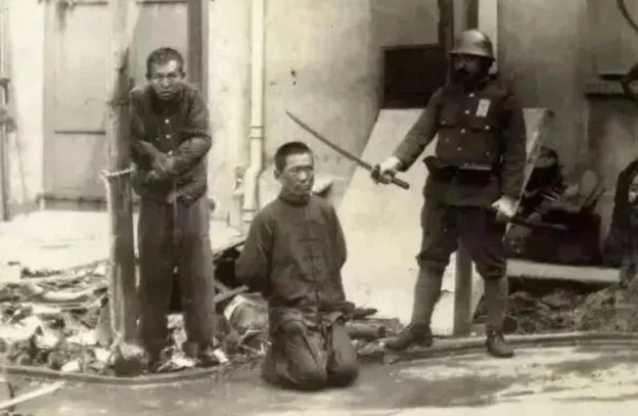 1937年12月南京沦陷期间，一名日寇拿着武士刀正准备砍杀两名平民百姓，两名百姓