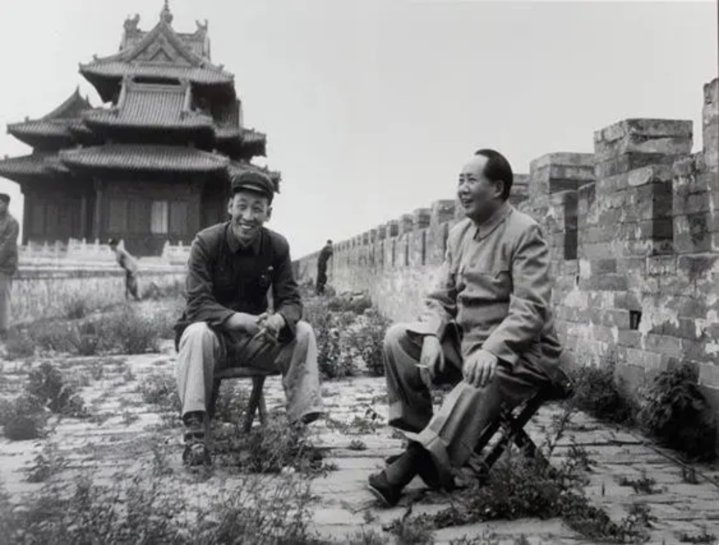 1954年，北京。故宫的城墙上，毛主席随意地坐在小板凳上和身旁的同志聊天。当时的