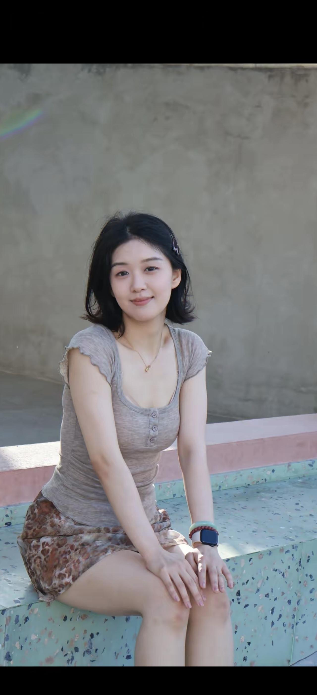 一个女孩坐在池边微笑。