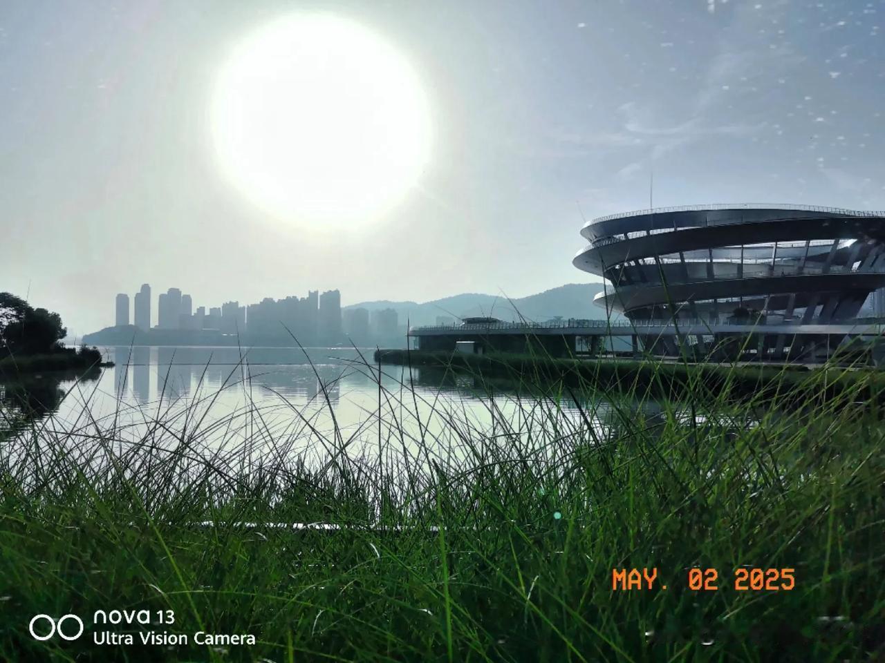 阳光洒满湖面，城市天际线倒映在波光粼粼的水中，现代建筑与自然美景交相辉映。湖面风