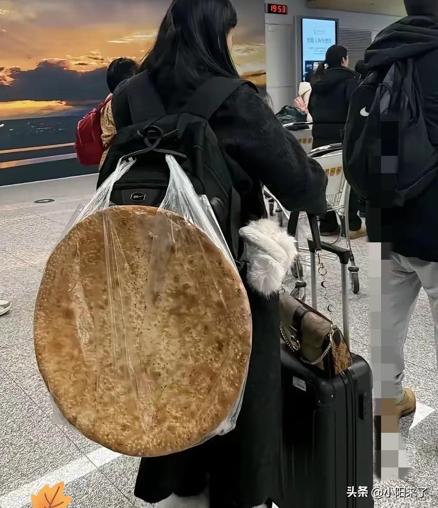 一女子在机场等着过安检，万万没想到女子的背上竟然背了一个硕大无比的馕，远看这馕占