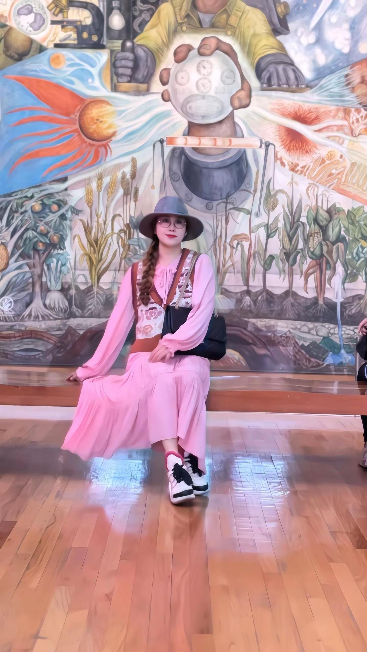 在《人，宇宙的控制者》壁画前，粉色裙摆与工业金属色撞出温柔的火花。画作把20世纪