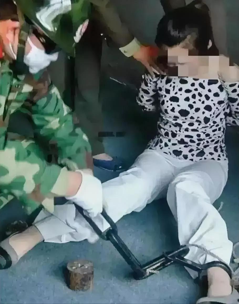 瘫坐在地上的美女是一名死刑犯，此时，法警正在给她卸下脚镣手铐，准备给她捆绑法绳，