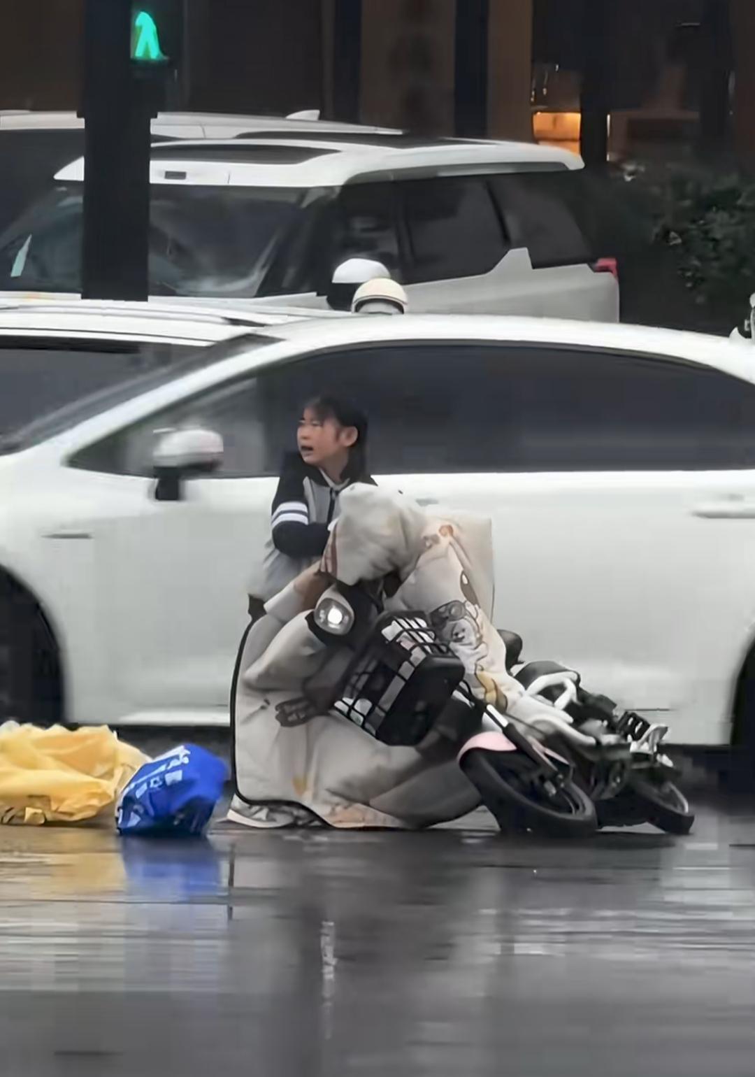 这才是我们该有的样子吧！

雨中一位家长骑车送孩子的时候，不小心滑倒在路中间。
