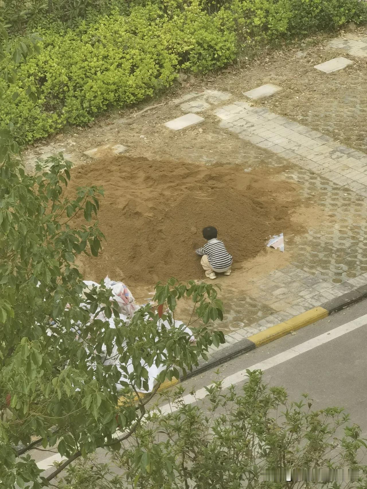 有没有小朋友很羡慕这孩子的？人地面堆着沙，小孩在“沙山”上爬上爬下，不亦乐乎。