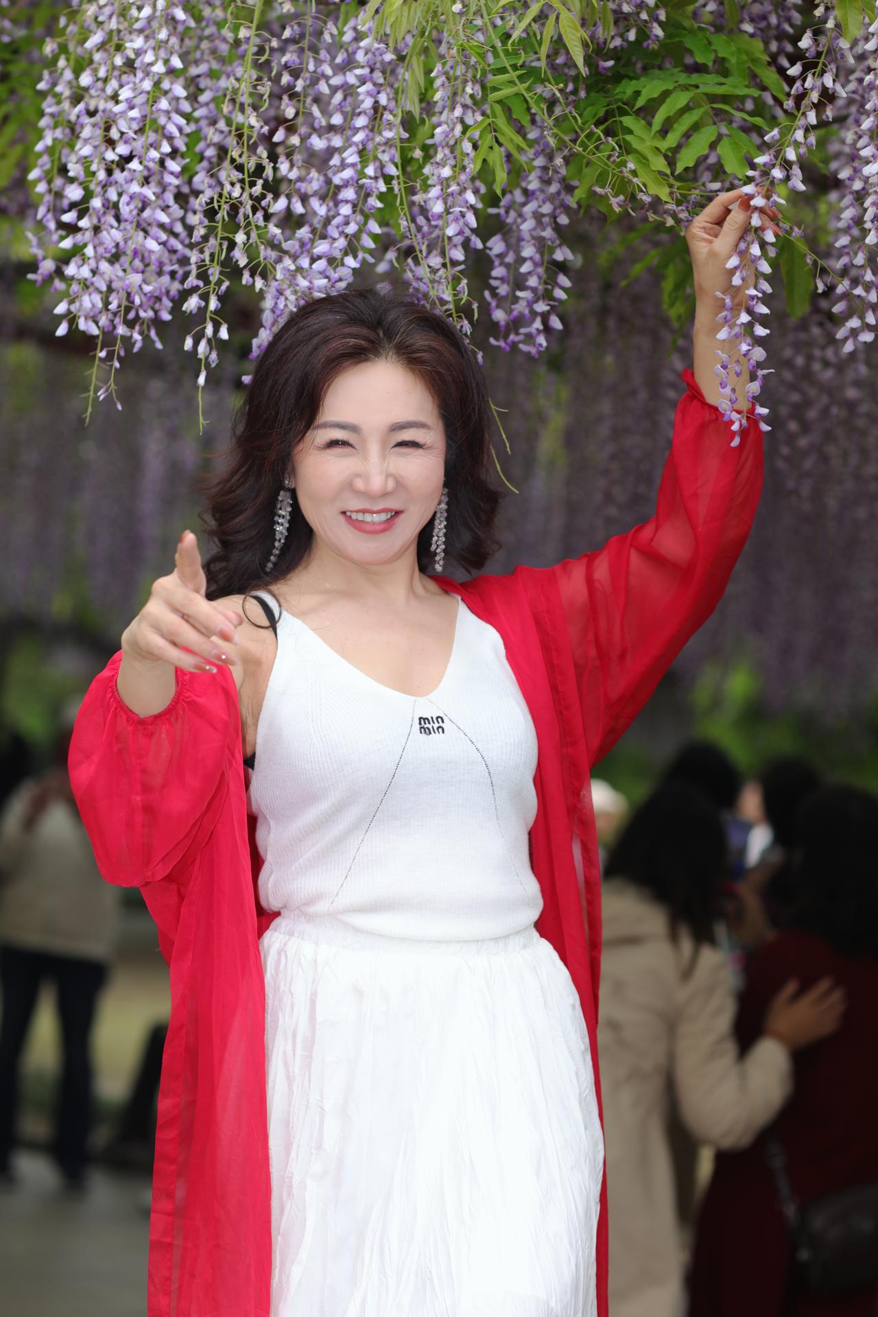 《紫藤花下的一抹红》
春风拂过紫藤花架，垂落的花穗像紫色的瀑布，在暖阳里漾着温柔