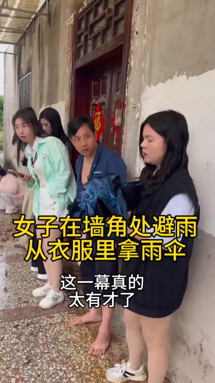 女子在墙角处避雨，从衣服里拿雨伞，这一幕真的太有才了。
天空突然下起了大雨，这时