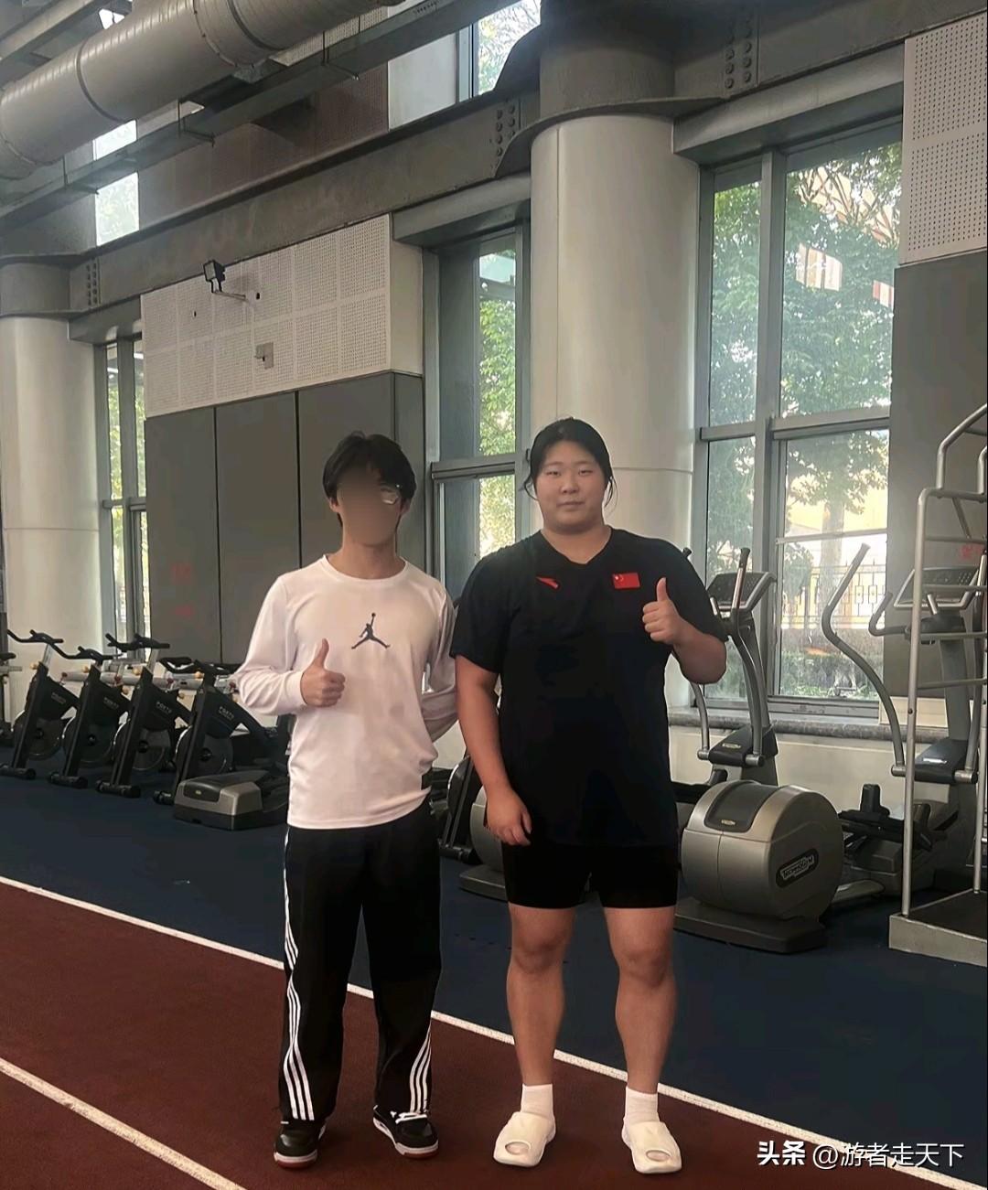 严子怡和普通成年男子站在一起的对比依然强烈，看室内的背景应该是一个大型的健身房，