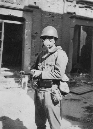 1937 年，日本上海海军特别陆战队，一名士兵手持三八式步枪，戴着九三式防毒面具