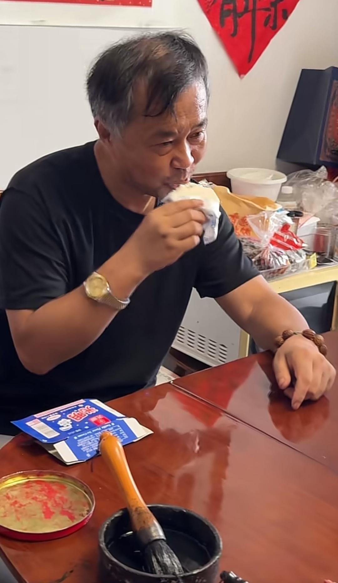 沈巍左手戴串，右手戴表，嘴里吃着光明冰砖，他既是普通俗人，也是“文化大师”。
手