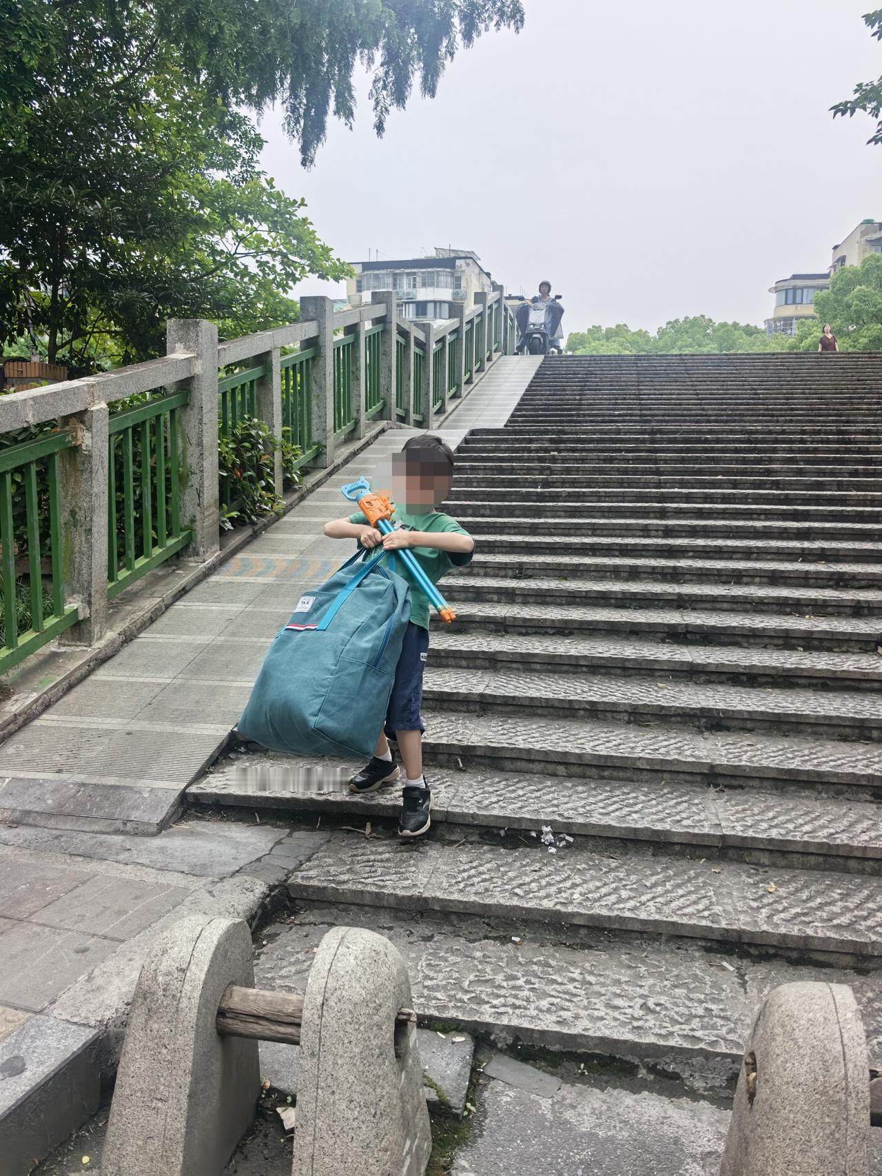 放学后电频车上挂着他幼儿园的被子，过桥下坡时有点挡住我的脚踩在地上，儿子主动说：