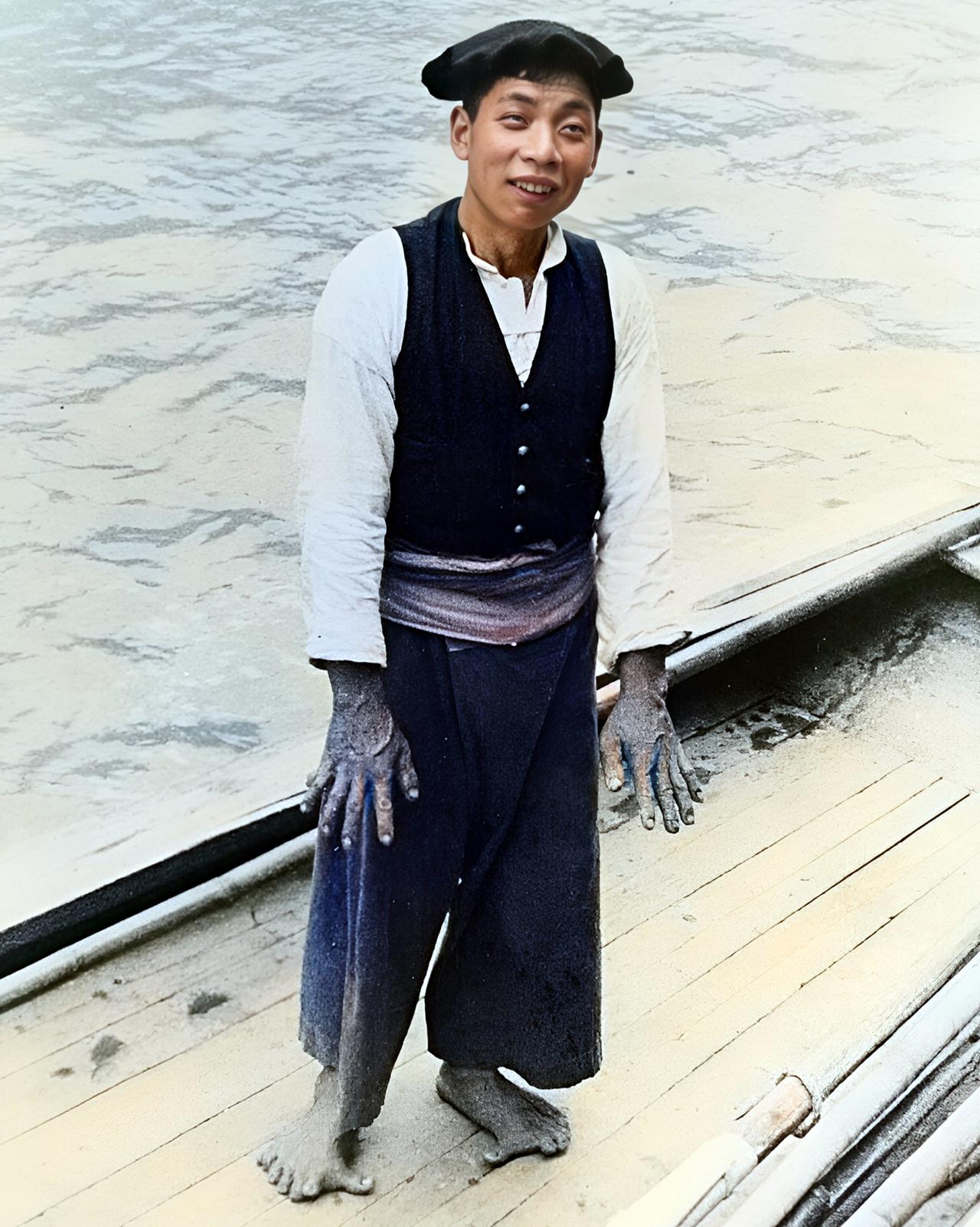 1935年，重庆，一位船夫站在江边的船上，面对镜头露出憨厚的笑容。

他身上的衣