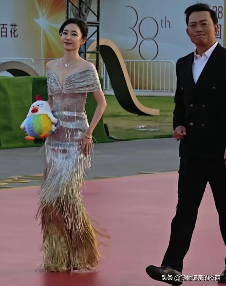 拿着娃娃穿长款杏色礼服裙的是素颜美女王丽坤，无论是身材和颜值都是这个年龄段里比较