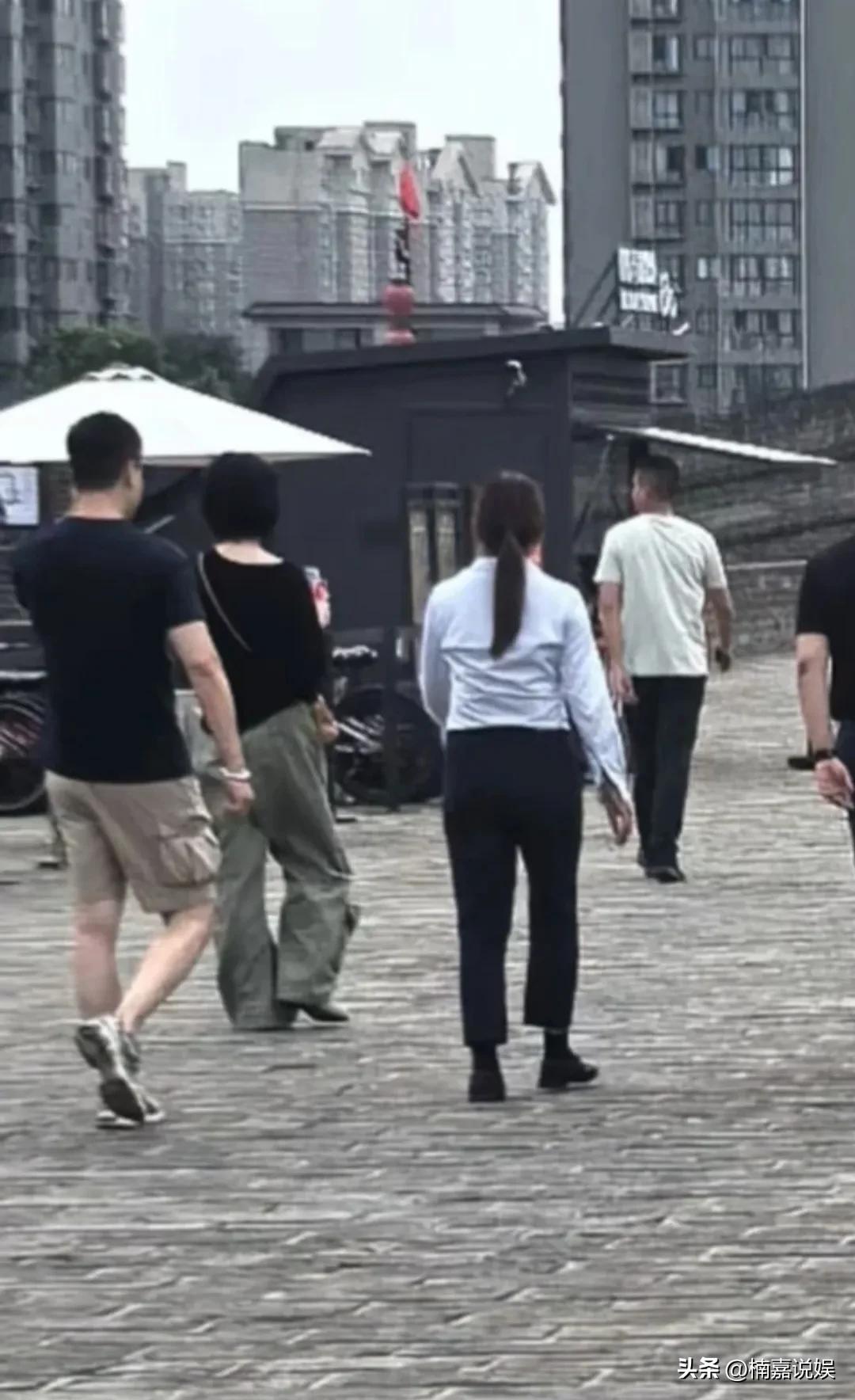 王菲到达西安后，现身西安古城墙。
她穿着一件黑色T恤配军绿色裤子，肤色超级白，个