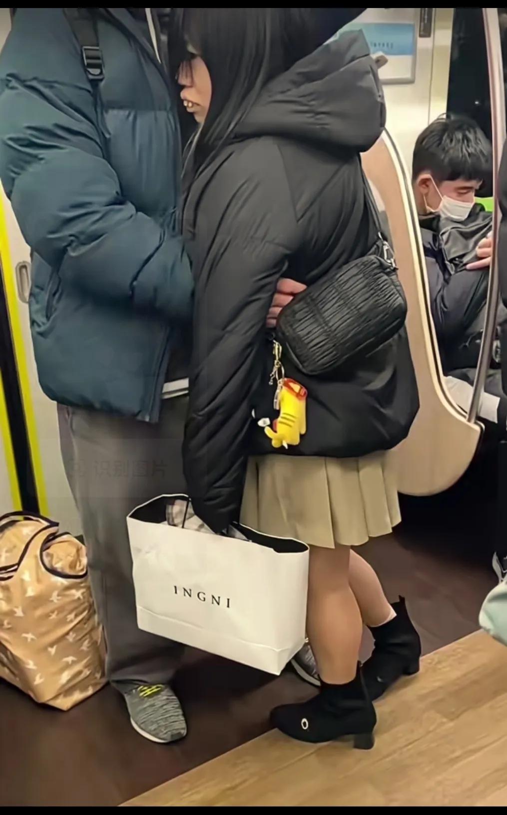 地铁上一对恩爱的情侣，女人撒娇靠男人的怀里，男人满眼宠溺的搂着她。