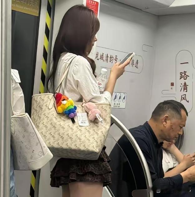 香肩挎名包，
上班乘公交。
无坐依门站，
端庄手机瞧。