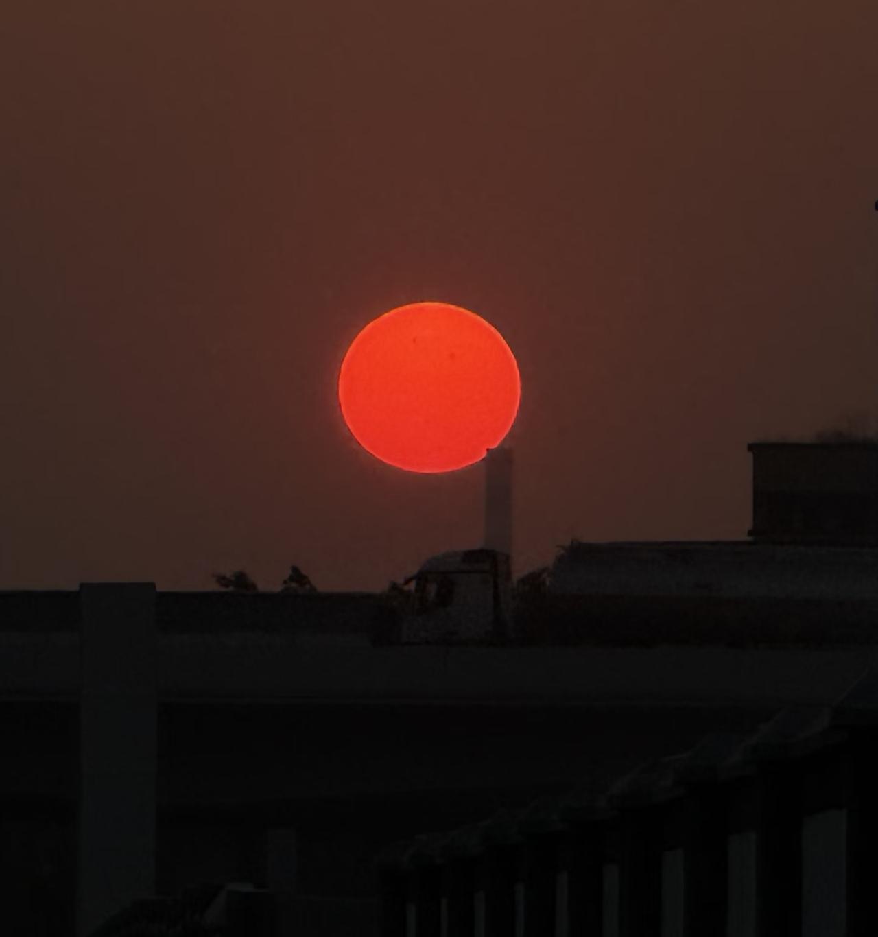 傍晚站在阳台收衣服，一抬头就撞见了这颗悬在城市上空的橘红色落日。它像一枚熟透的柿