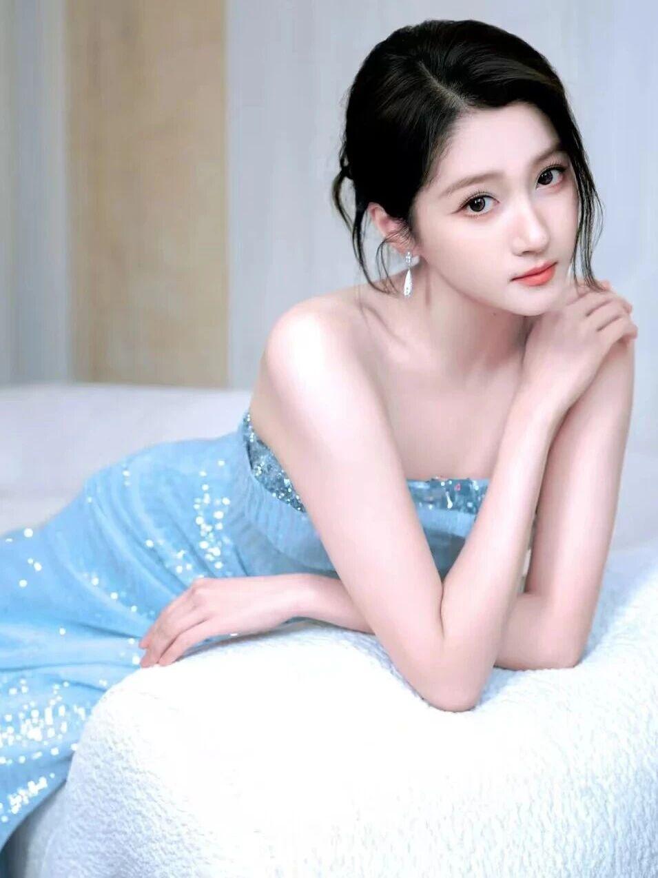 想象一下，在一个阳光慵懒的午后，一位身着优雅蓝裙的气质女神，静静地坐在公园的长椅