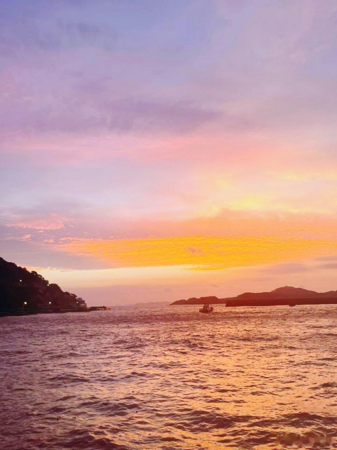 看着晚霞从粉紫晕染成橘红，再慢慢沉落进海面，海浪把漫天霞光揉碎在波纹里。孤船静静