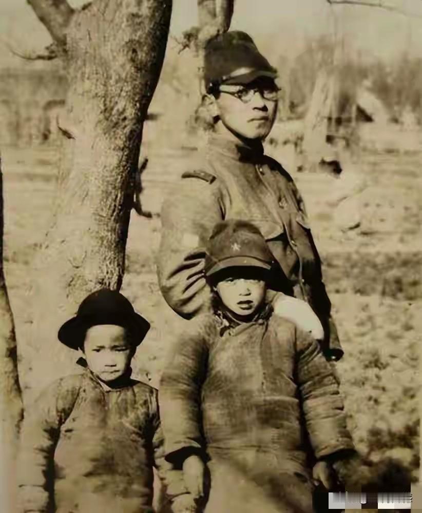 两个穿着棉袄、戴着帽子的孩子，站在日本鬼子身边照相，能够看出他们的表情是非常紧张