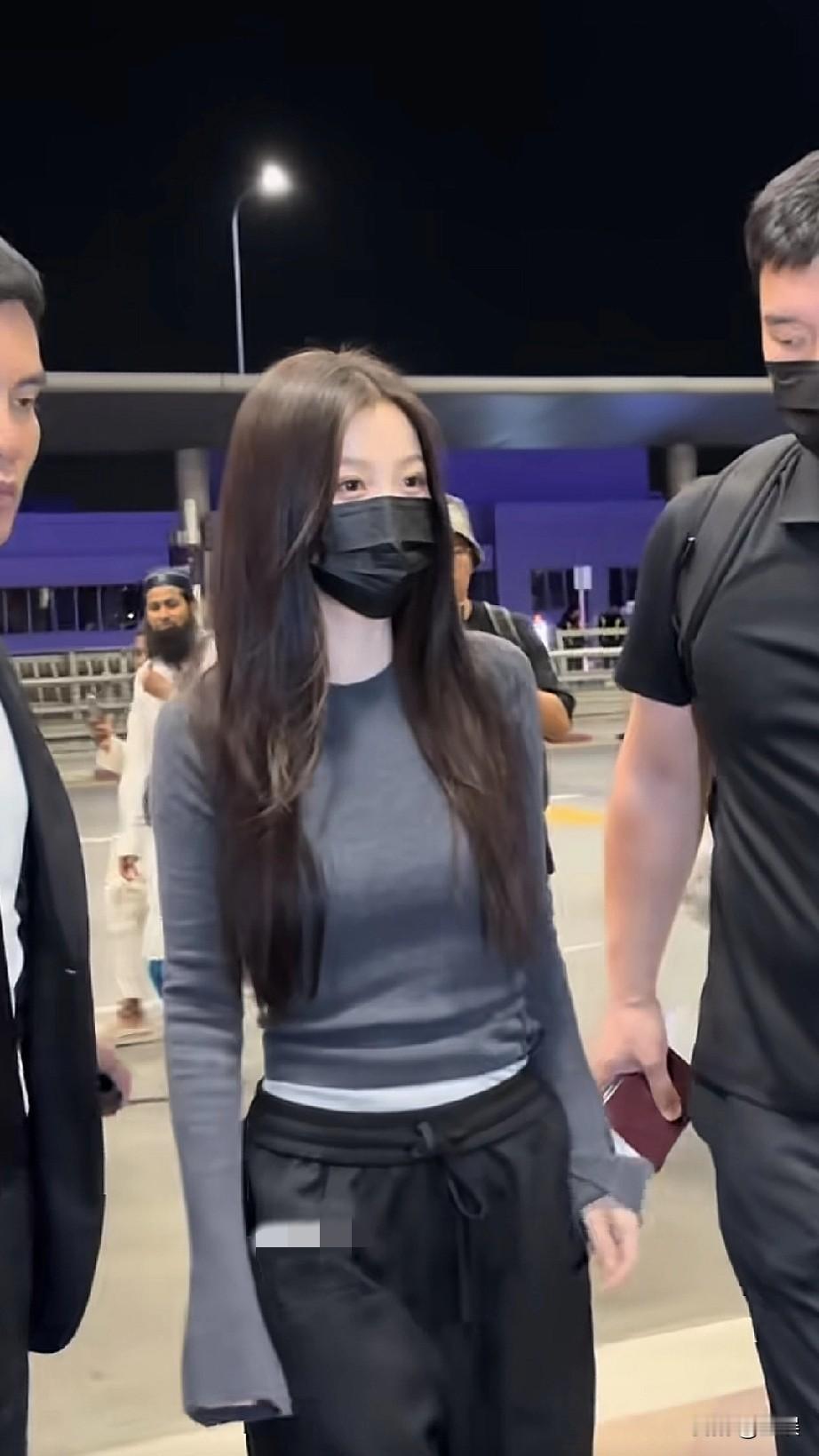 夜幕下的机场，虞书欣一身简约穿搭，灰色修身长袖内搭白色打底，搭配黑色休闲裤，长发