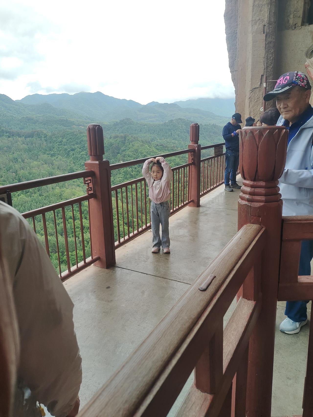 麦积山石窟随拍
登上麦积山石窟，我看到一对夫妻正在给一个小女孩拍照。
小女孩变换