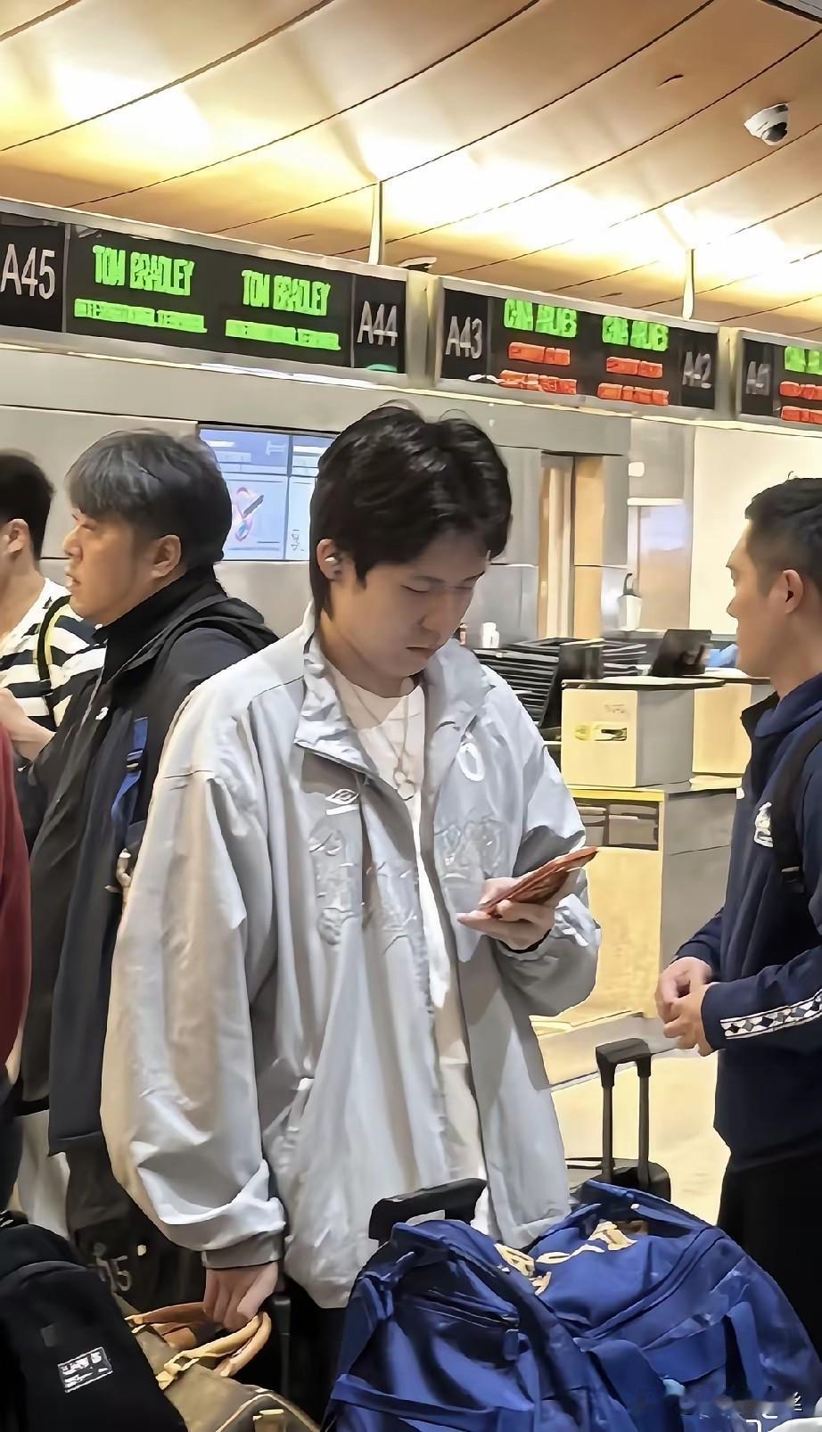 国乒大部队回国了，
楚钦一会摸一下背包上的小公仔，
一会和周启豪聊会天，
肉眼可