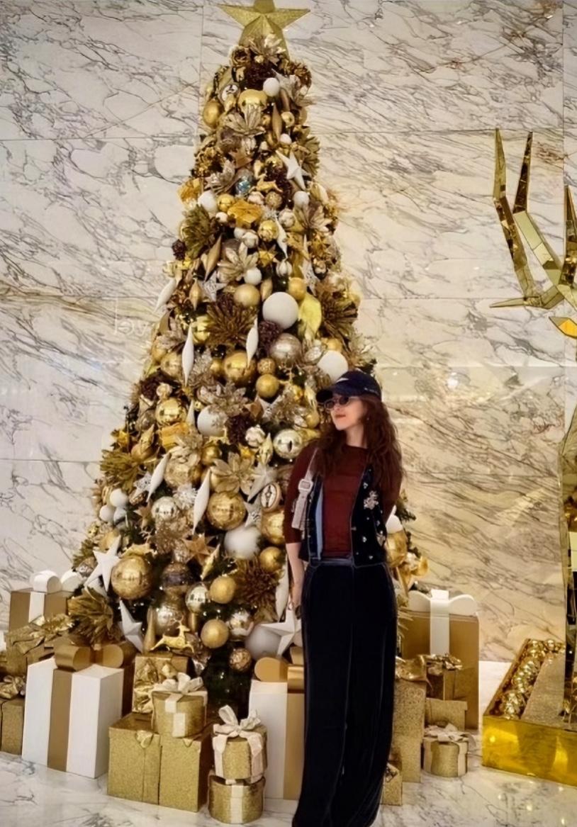 章泽天圣诞晒迪拜近照，酒红内搭配阔腿裤，站金色圣诞树旁状态慵懒。她今年当《VOG
