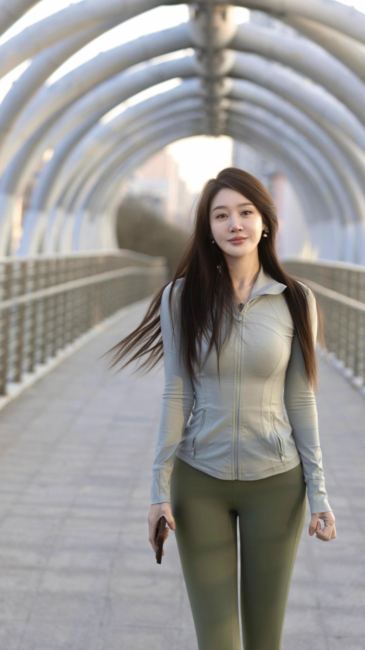 暮色里的行歌
 
晚风掠过金属拱廊的弧度
把长发揉成流动的暮色
浅灰的衣料裹着舒