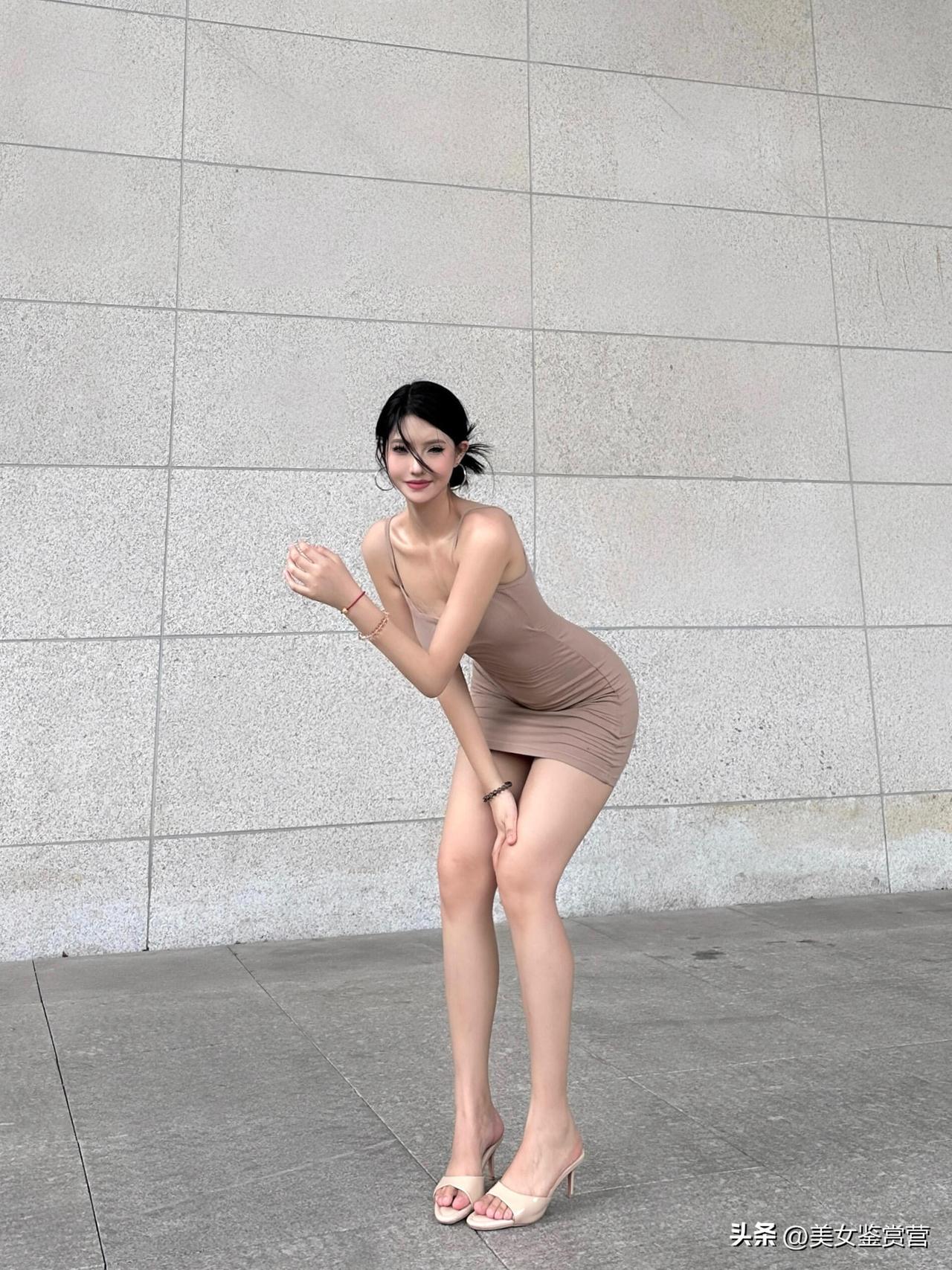 卡其色吊带短裙勾勒出柔和的曲线，与背景的石墙质感形成对比，既显利落又不失温柔。裸