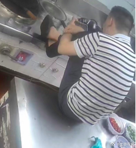 #宁波一外卖店后厨男子脚踩灶台#【紧挨着炒锅和备菜，宁波一外卖店后厨男子穿鞋踩灶
