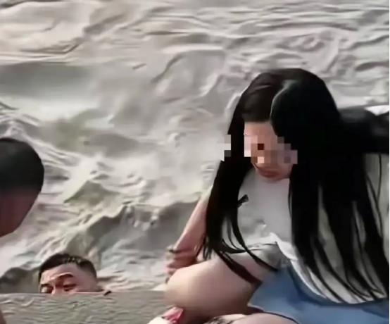 武汉汉口，一女子站在江滩边，丈夫给她拍照，突然丈夫扔下手机，纵身跳入江里。而妻子