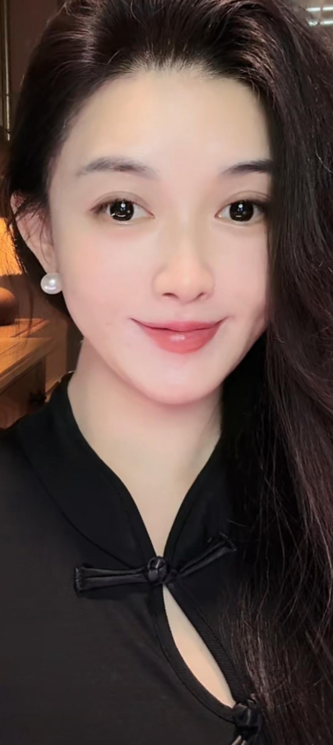 这位美女穿着黑色蝴蝶结上衣，微笑着看镜头。