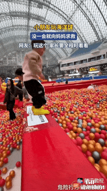 一个小男孩从台阶上猛地跳进海洋球池，刹那间，孩子就被海洋球完全淹没了。孩子在球堆