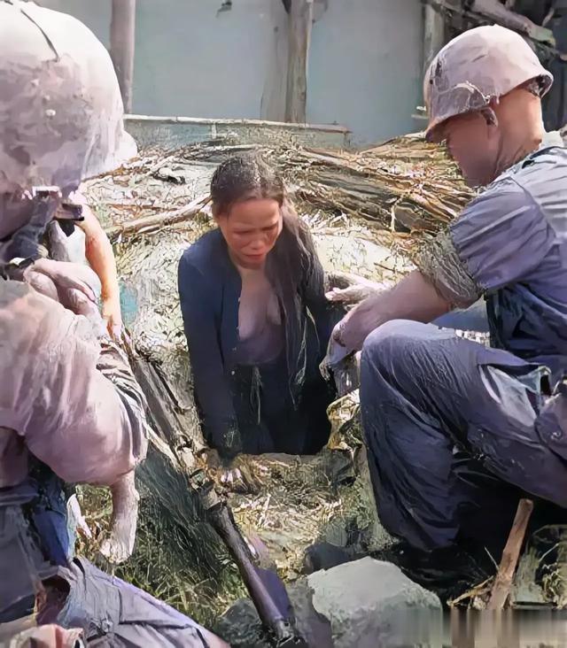 一位越南妇女被美军发现躲藏在地窖中，她艰难地爬了出来，面容表露出痛苦和泪水。

