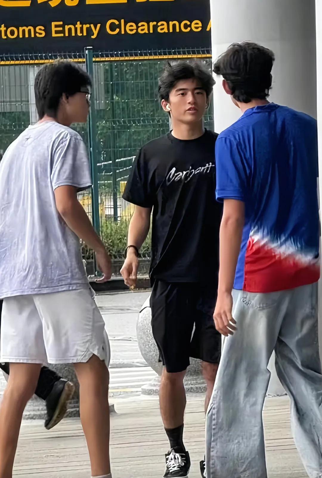 谢霆锋的18岁大儿子谢振轩和同学现身深圳口岸，他穿着一身黑衣，戴着耳机，头发茂密