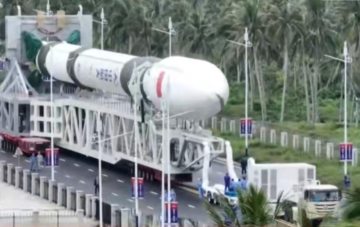 运载火箭在转运轨道上缓缓前行，白色箭体与热带绿植相映，勾勒出中国航天的坚实步履。