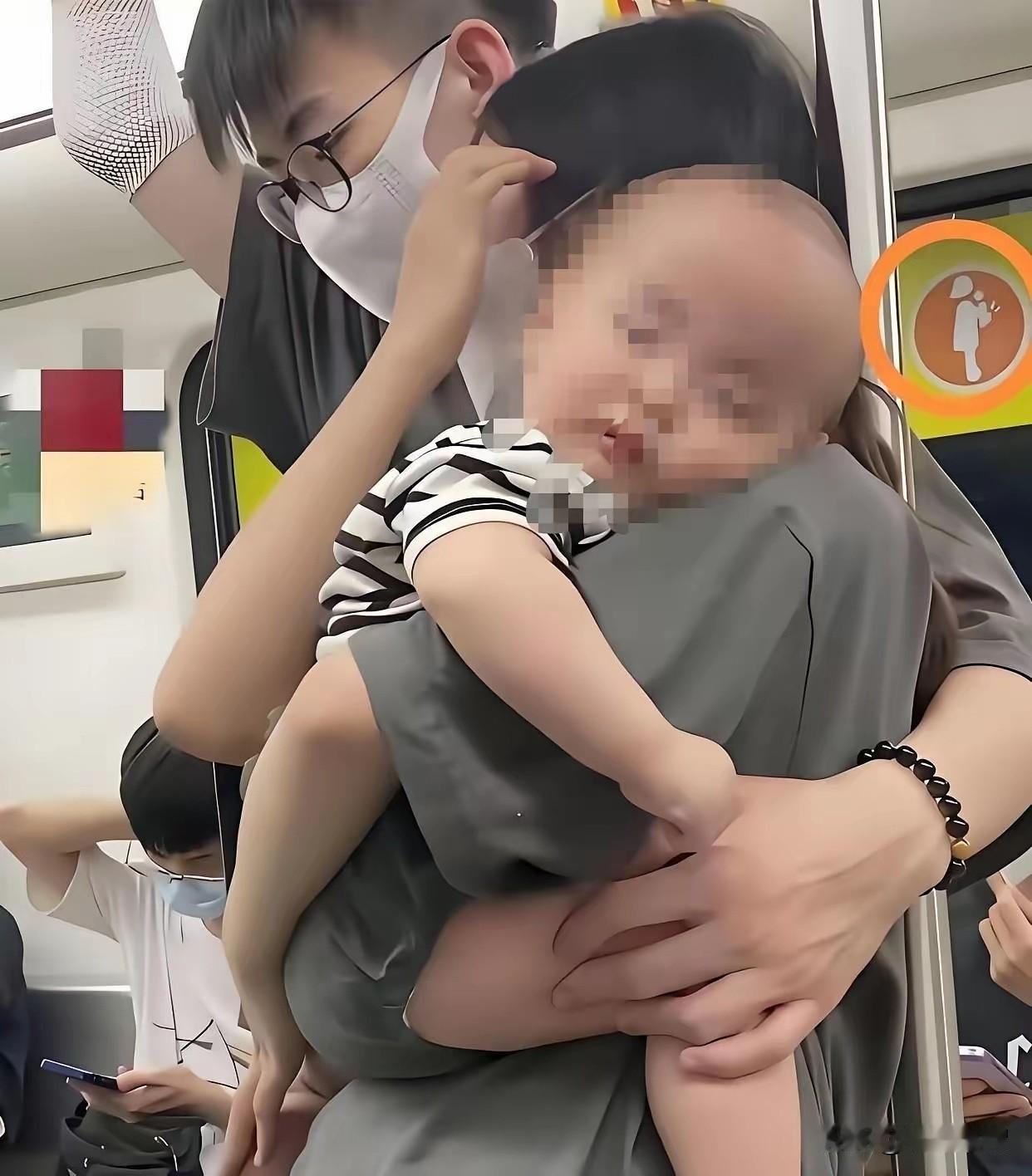 女子双手抱着孩子，靠在铁杆上。孩子趴在女子肩上睡着了，孩子的爸爸怕女子站不稳，双