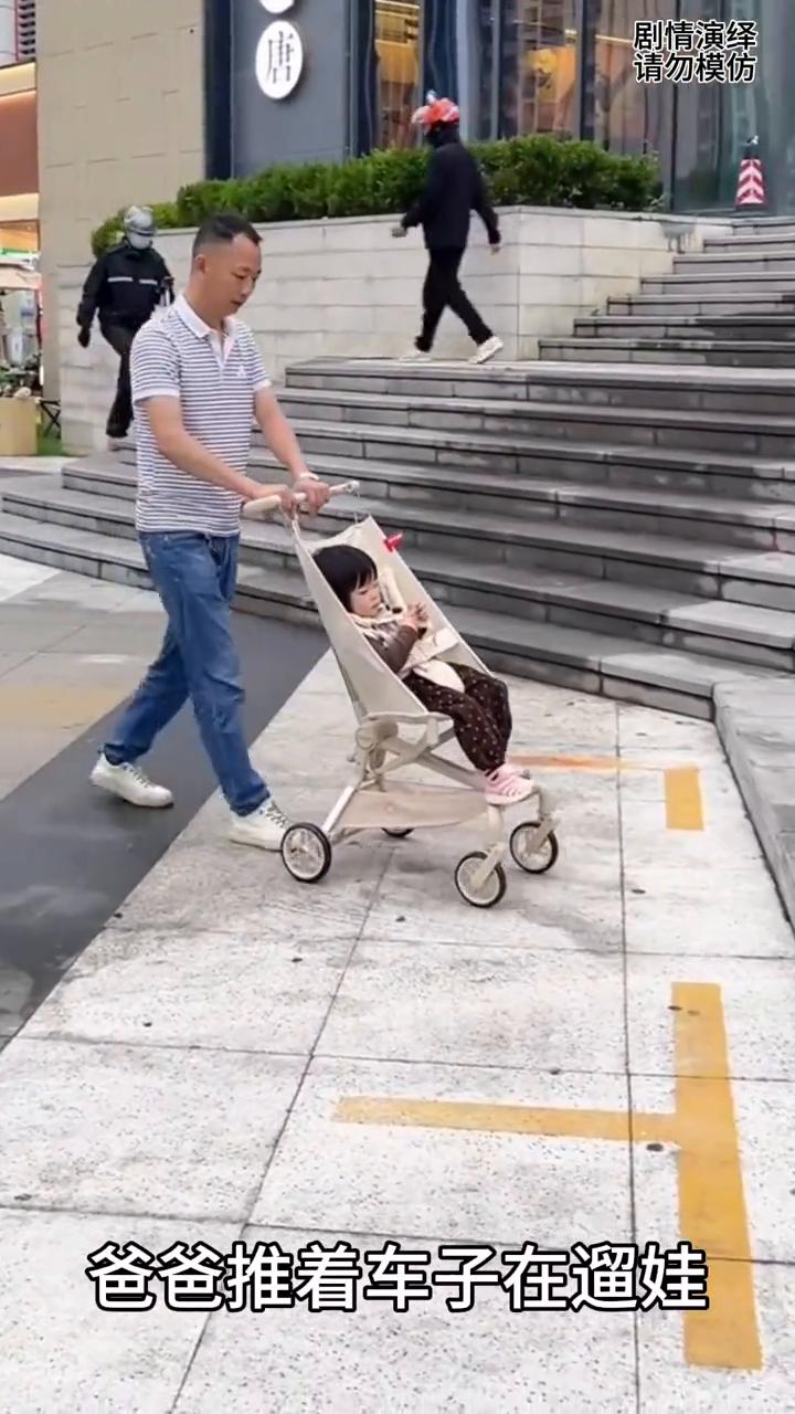 爸爸推着车子在遛娃，就当他们走到台阶处，下一秒爸爸将车子往前趴，随后宝宝走着上台