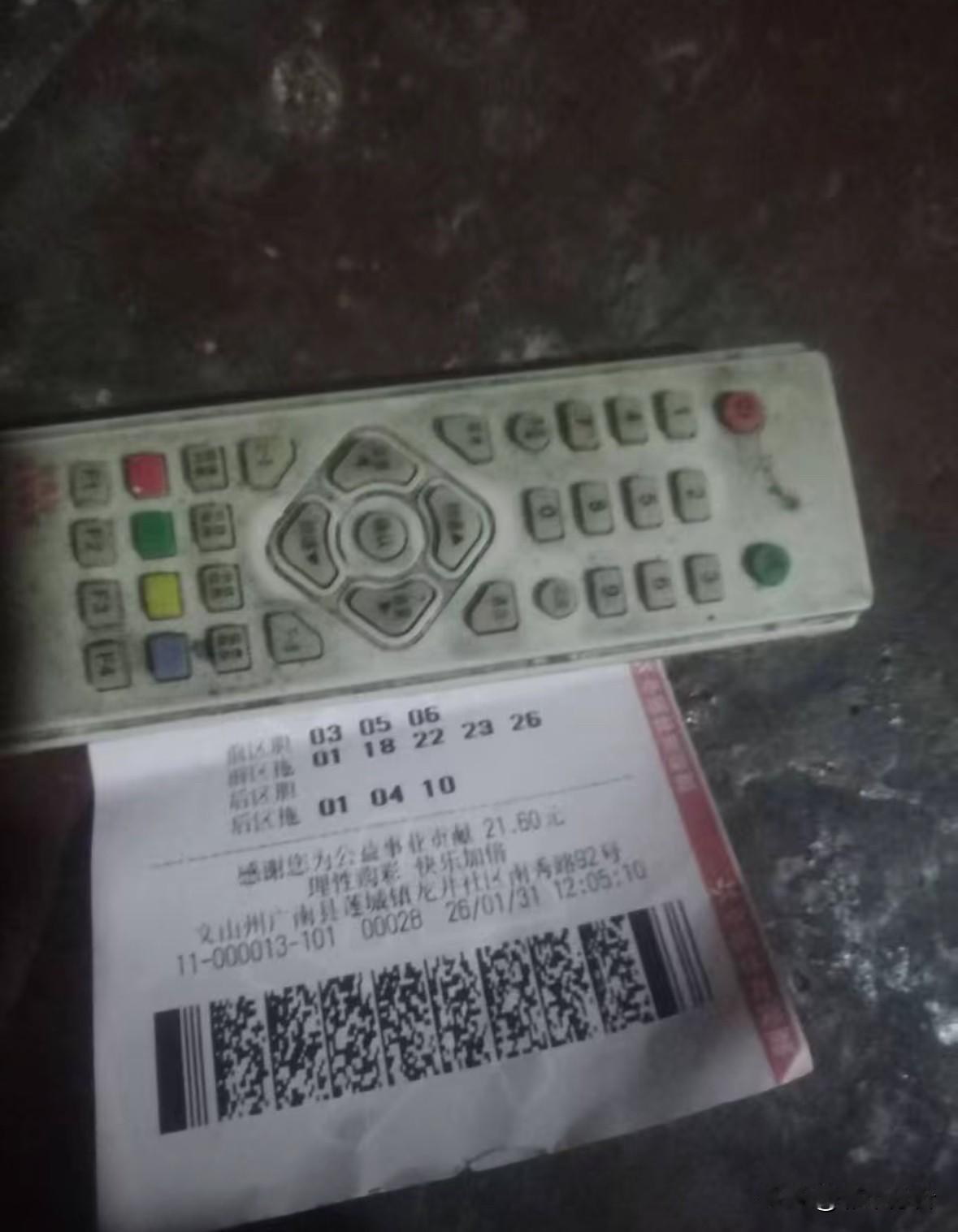 622万得主应该是个穷苦人：晒票背景黑黢黢，用来遮挡序列号的电视遥控器也有脏，桌