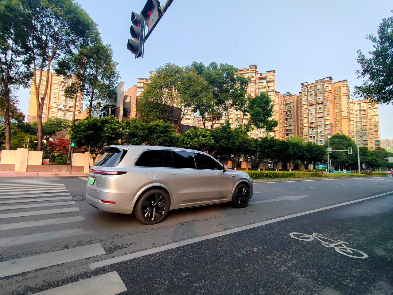 晨光漫过天际，为高楼披上流动的金色。路上行车驶入画面，轮廓在曦光中显得格外柔和。