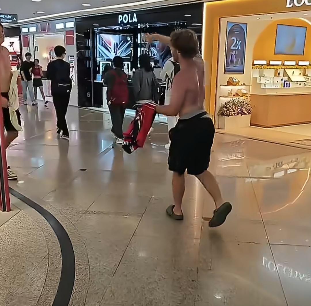 几名光膀子外国男子，挤着电梯进入香港地铁站，他们一路大呼小叫，吵闹声和过往乘客的