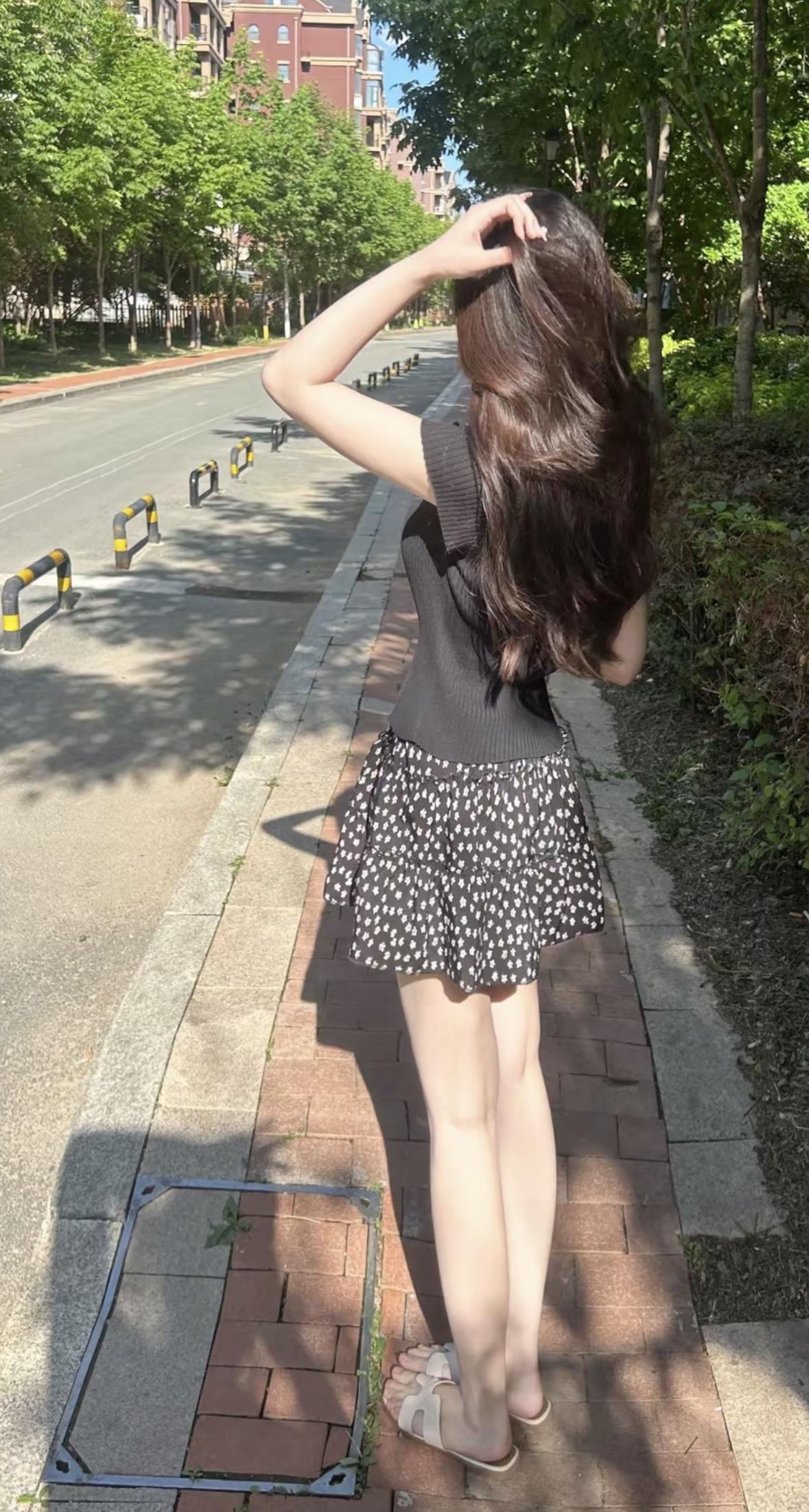 一个女孩站在路边整理头发。