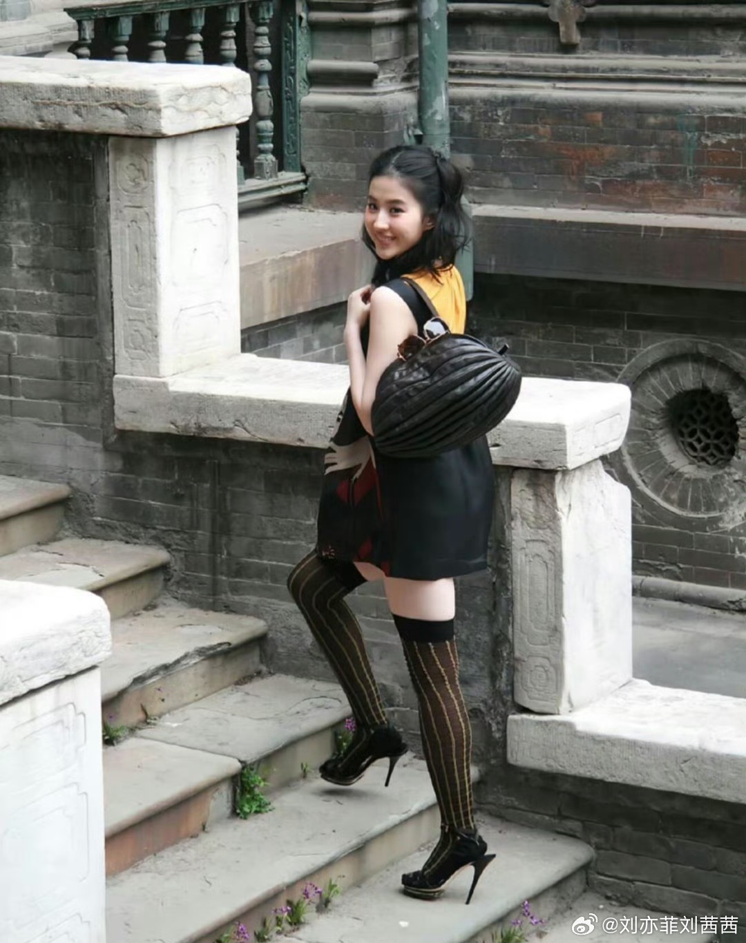 刘亦菲选择的是一件无袖撞色印花A字短裙，黑底搭配红、白抽象图案，内搭明黄色小高领