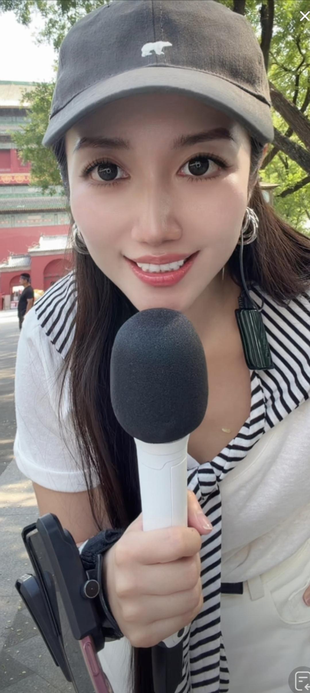 这位美女拿着麦克风在户外。