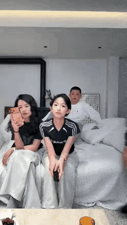 老婆女儿和儿子坐在床上看电视，爸爸过来坐在姑娘的旁边，偷摸递给姑娘一百元钱，女儿
