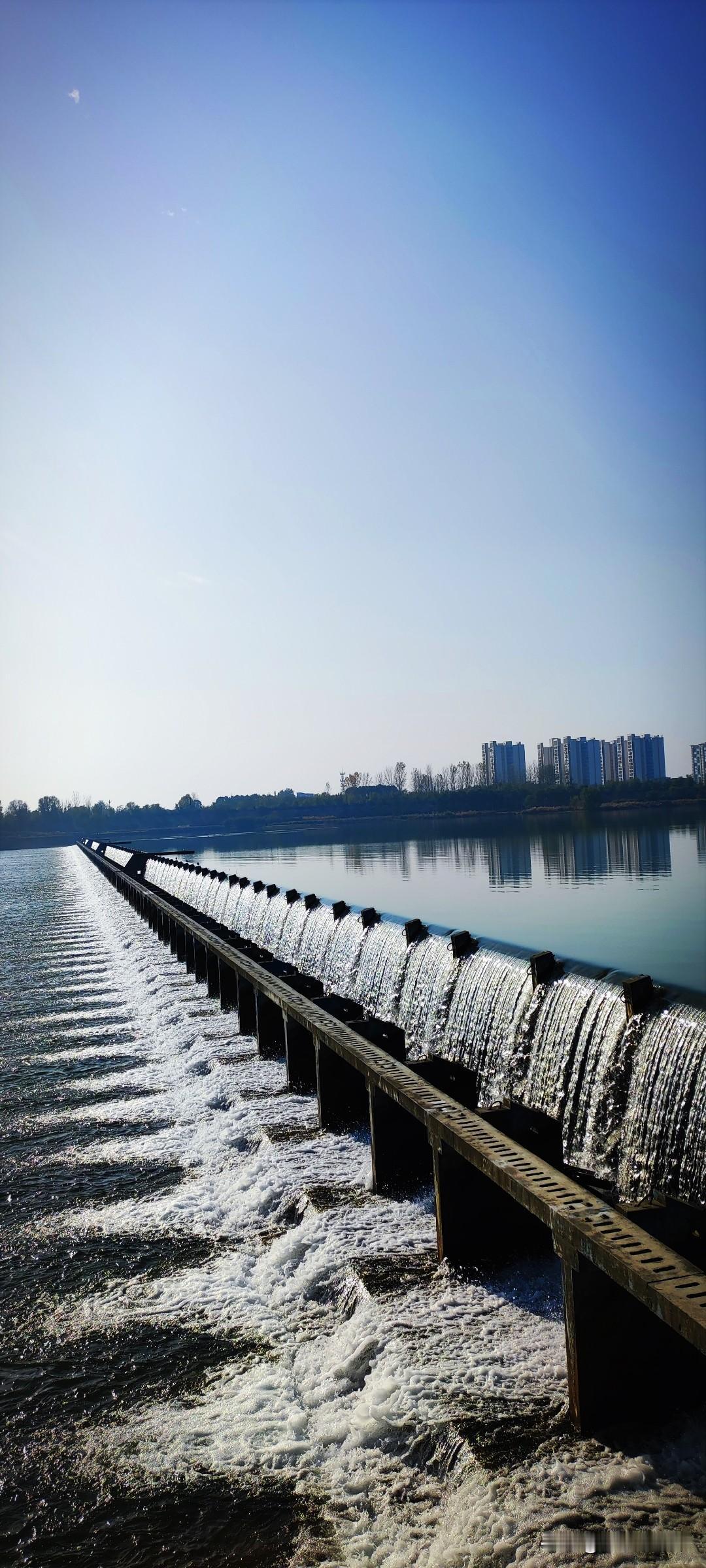 冬日生活打卡季汉江湿地公园，一道翻板横贯江面，哗哗的水瀑犹如一道帷幕，水波如镜的